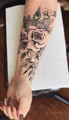 a woman's arm with flowers and a crown on it