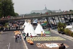 many people are walking on the sidewalk near some tents