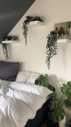 there is a bed with white sheets and plants on the headboard in this room