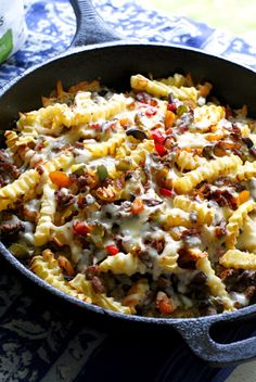 a skillet filled with pasta and meat covered in cheese, sauce and other toppings