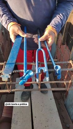 a person standing on top of a wooden structure holding onto two blue handles with one hand