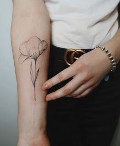 a woman's arm with a flower tattoo on the left side of her arm