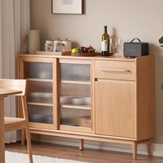 a wooden cabinet with glass doors in a living room next to a table and chair