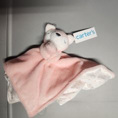 a stuffed animal wrapped in a pink blanket with a name tag hanging from it's side