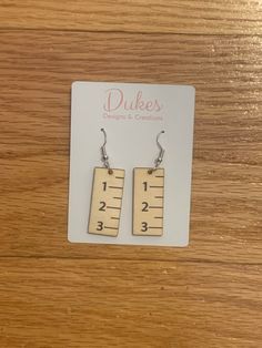 pair of wooden earrings with measuring tape on them