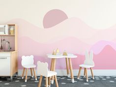 two chairs and a table in front of a wall with a pink design on it