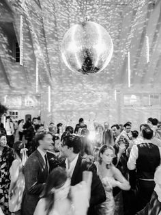 a group of people standing around each other in a room with disco balls hanging from the ceiling