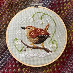 a cross stitched picture of an owl on a branch