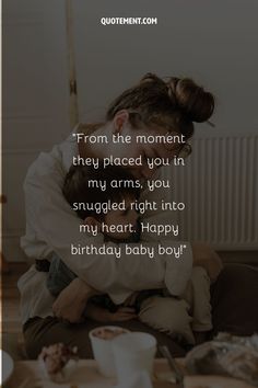 a woman hugging her baby on the floor with a birthday message in front of her