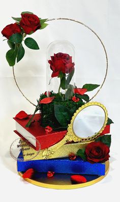 red roses are in a glass vase on top of two books and a magnifying glass