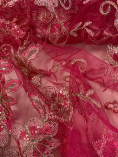 pink and gold embroidered mesh fabric with flowers on the side, closeup view in full frame