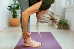 an older woman doing yoga on a purple mat