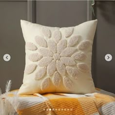 a white pillow sitting on top of a bed next to a yellow and white blanket