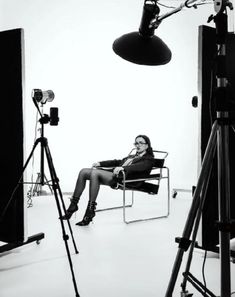 a black and white photo of a woman sitting on a chair in front of a camera