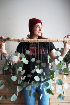 a woman holding up a piece of wood with leaves attached to it