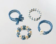 three bracelets and two rings are shown on a white surface, one is blue