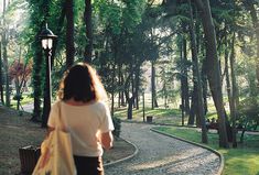 a woman walking down a path through a park