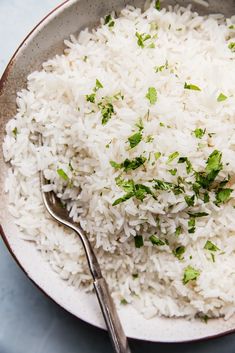 white rice in a bowl with a spoon on the side and parsley sprinkled on top