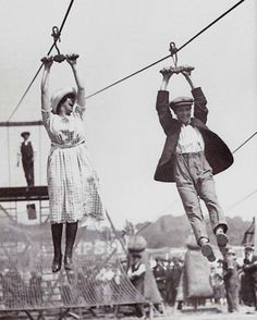 an old photo of two people hanging upside down in the air with ropes attached to them