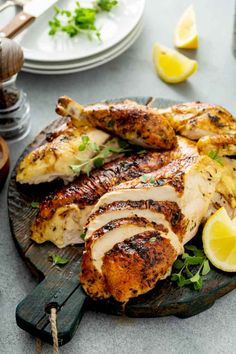 grilled chicken with lemon wedges and parsley on a wooden platter, ready to be served