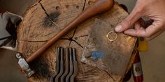 a person holding a knife and ring on top of a piece of wood next to other tools