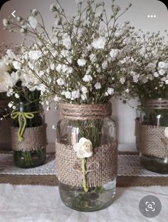 three mason jars with flowers in them are sitting on a tablecloth covered placemat