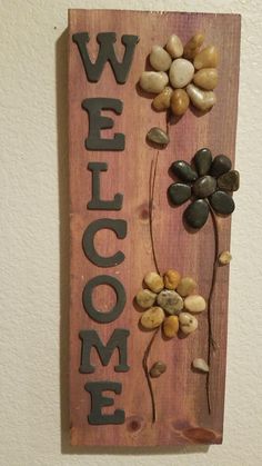 a wooden sign that says welcome with flowers and leaves on it, hanging from the wall