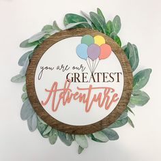 a wooden sign that says, you are the greatest adventure with balloons on it and leaves around it