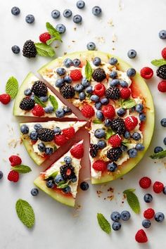 a fruit pizza with berries and mint leaves