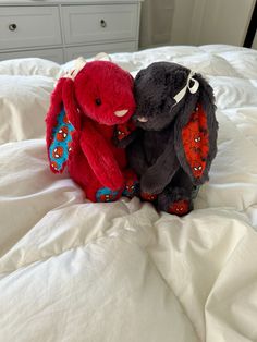 two stuffed animals sitting on top of a bed