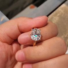 a person holding an engagement ring with a diamond in it's middle finger,