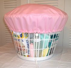 a white basket filled with lots of items on top of a table next to a wall