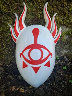 a white frisbee with red designs on it sitting in the dirt near grass