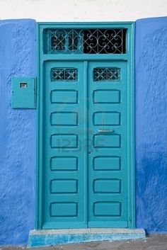 a blue and white building with two doors on each side, one has a window