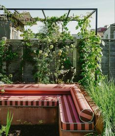 an outdoor hot tub in the middle of a garden with plants growing around it and a bench on the other side