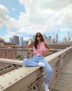 a woman sitting on top of a bridge next to a tall building