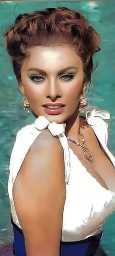 a woman posing in front of a pool with her hands on her hips and wearing large earrings