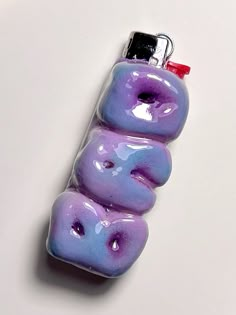 three purple donuts are wrapped in plastic and have been placed together to form the shape of a lighter