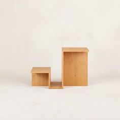 two small wooden boxes sitting next to each other on a white surface in front of a plain wall