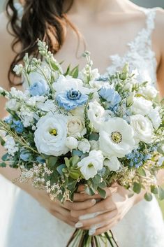 a bride holding a bouquet of white and blue flowers