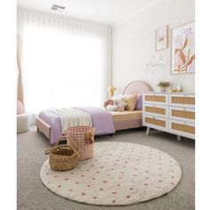 a child's bedroom with pink and white decor, including a round rug on the floor