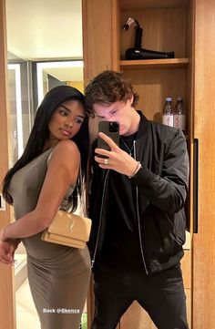 a man taking a selfie with a woman in a dress and black leather jacket