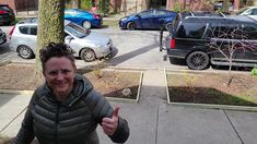 a woman giving the thumbs up in front of parked cars