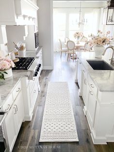 a kitchen with white cabinets and flowers on the counter top in front of an oven