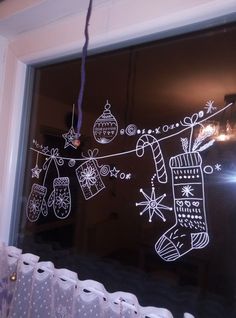 a window with christmas decorations drawn on the glass and hanging from it's side