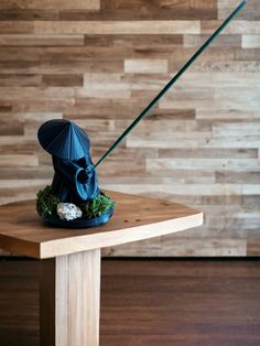 a wooden table topped with a blue hat and an umbrella on it's head