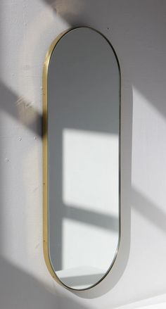 a white wall with a gold framed mirror on it