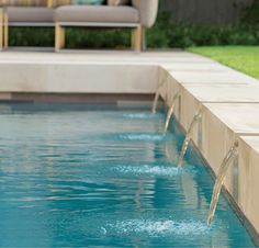 a pool with water running from it and a couch in the background