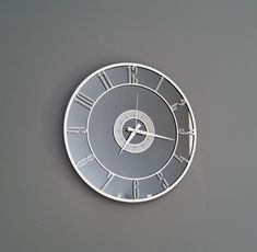 a clock with roman numerals is shown on a gray wall and grey background