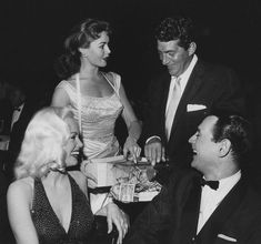 an old black and white photo of three people at a party, one holding a present